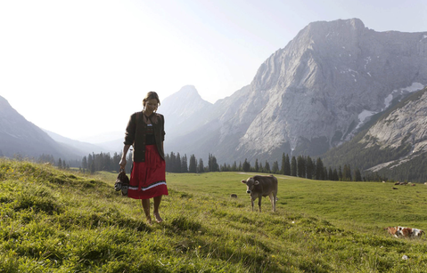 Woman in traditional costume with cows on a mountain pasture
